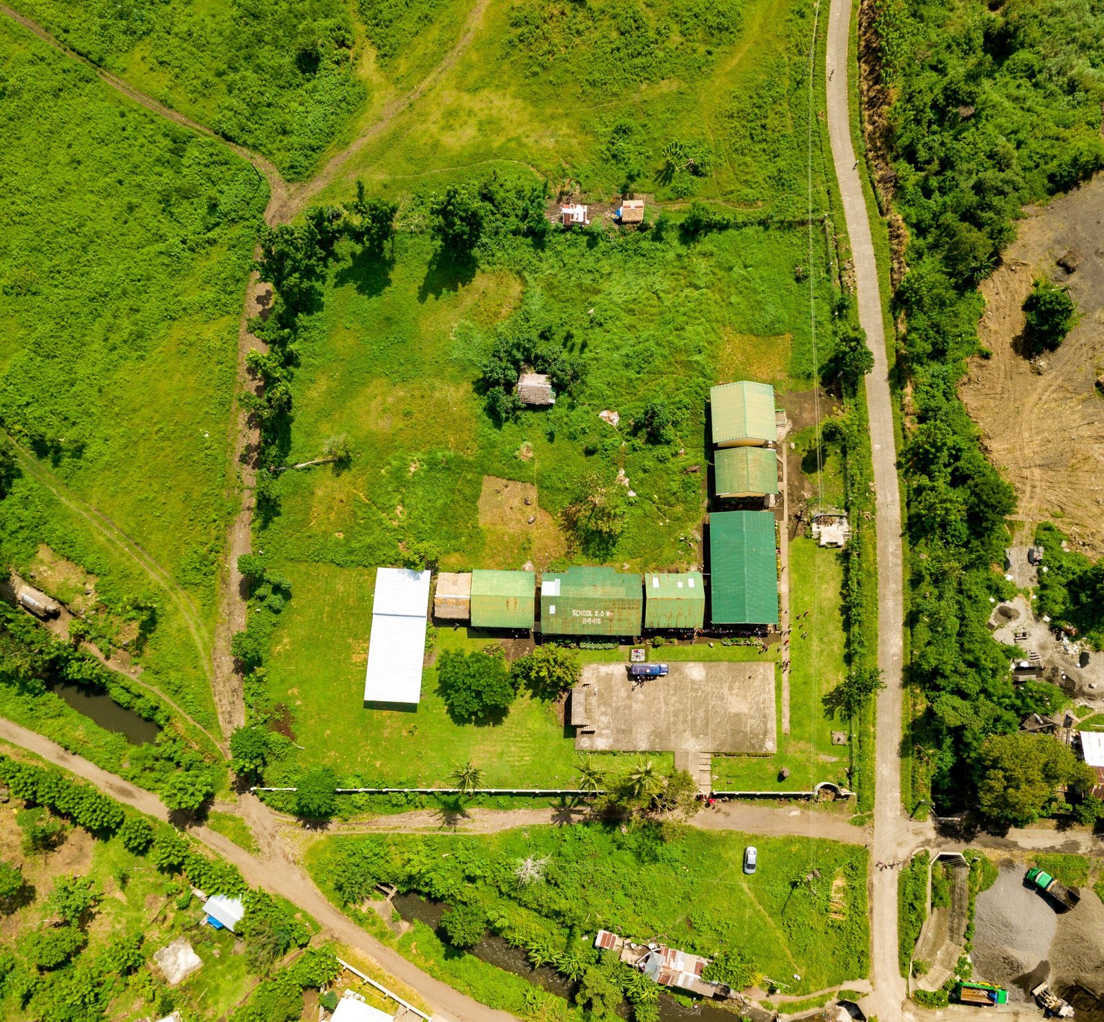 Aerial shot showcasing rural farmland with buildings, roads, and greenery.
