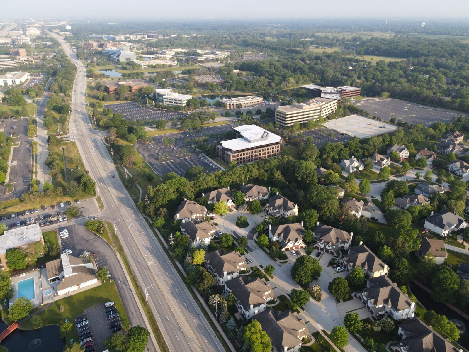 Aerial photo showcasing suburban Lisle, IL with roads, trees, and buildings under clear skies.
